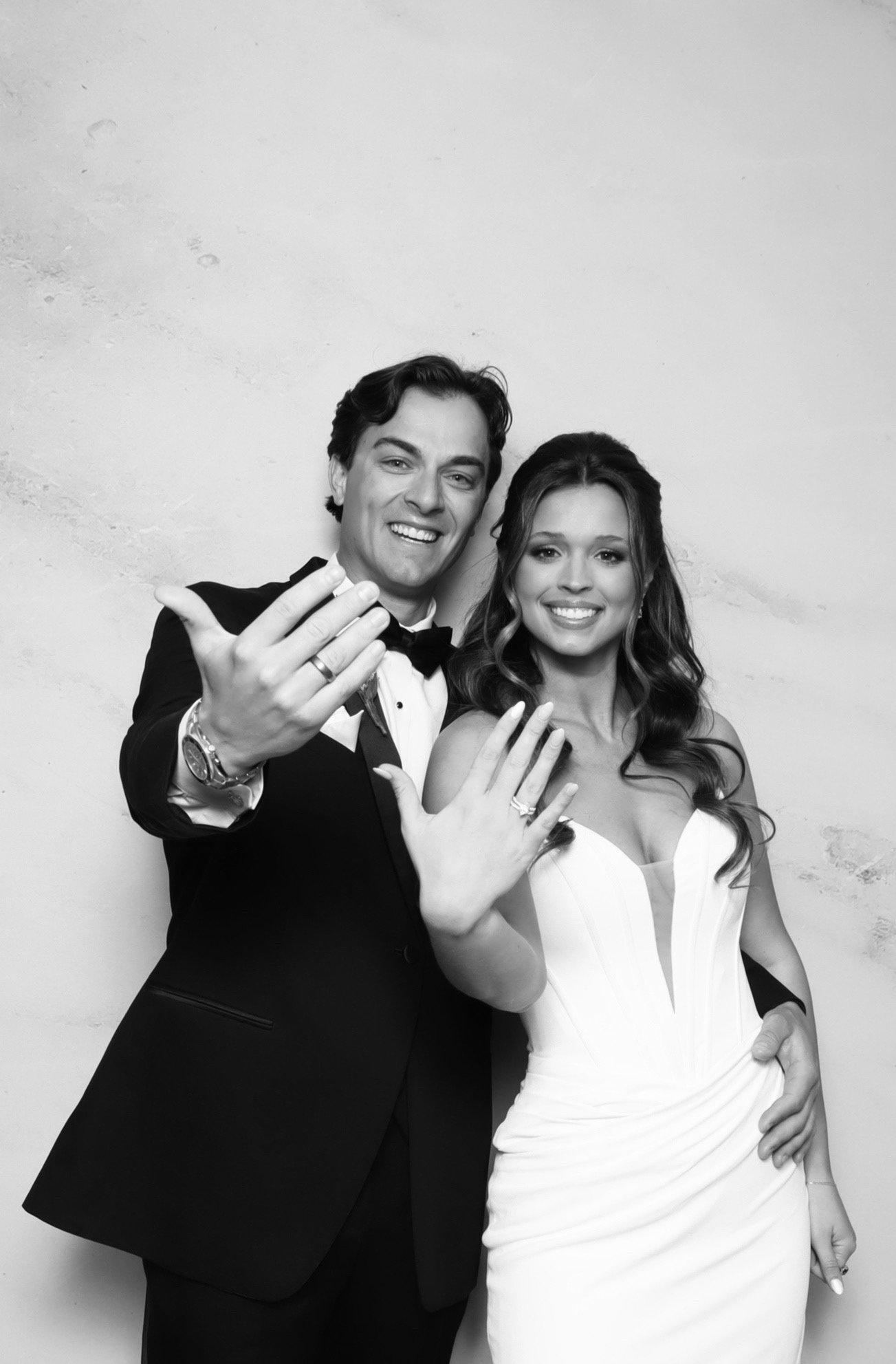 A black and white photo of a couple showing their rings.