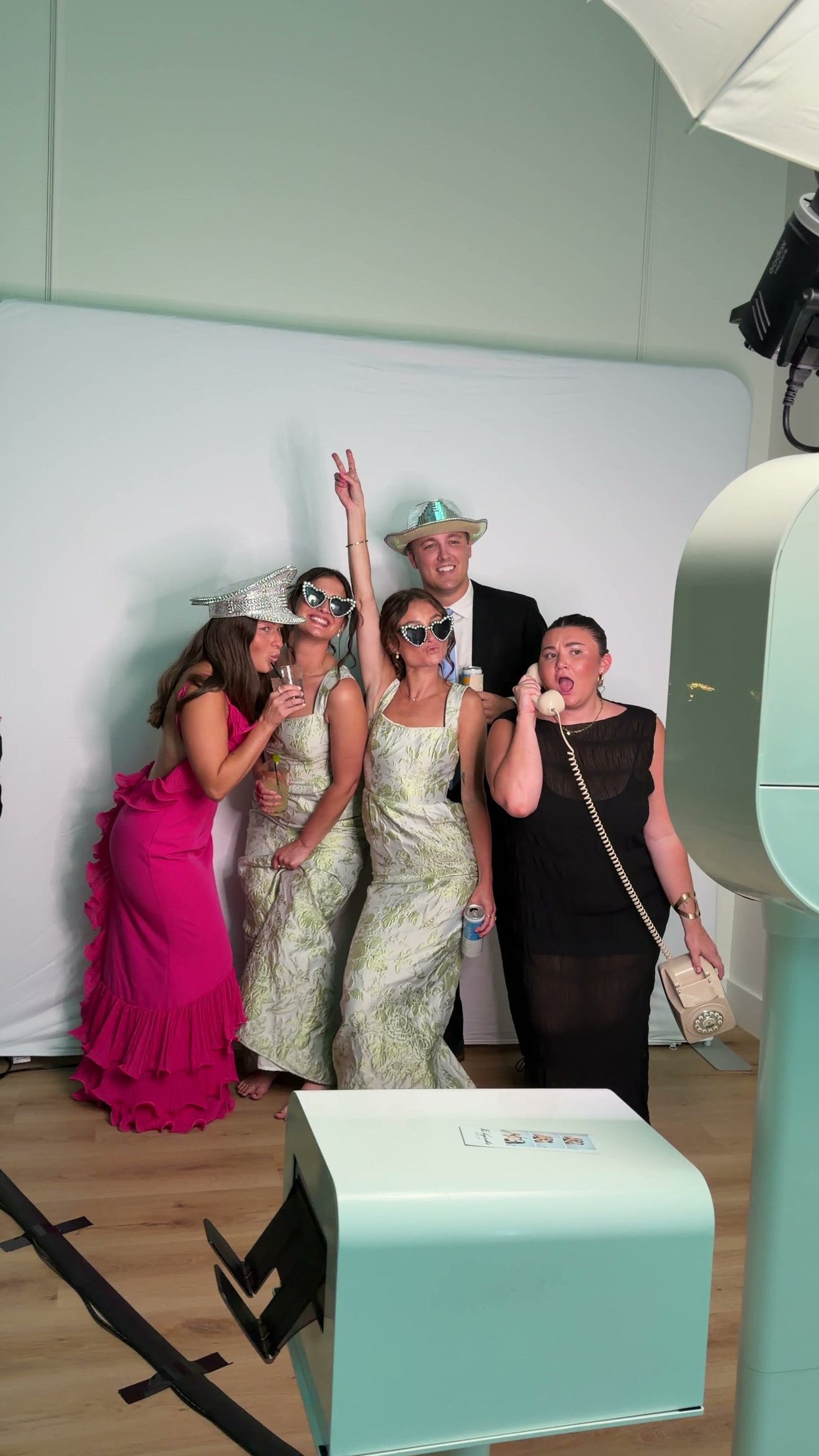 A guest talking into the retro telephone at the booth while her friends pose beside her.