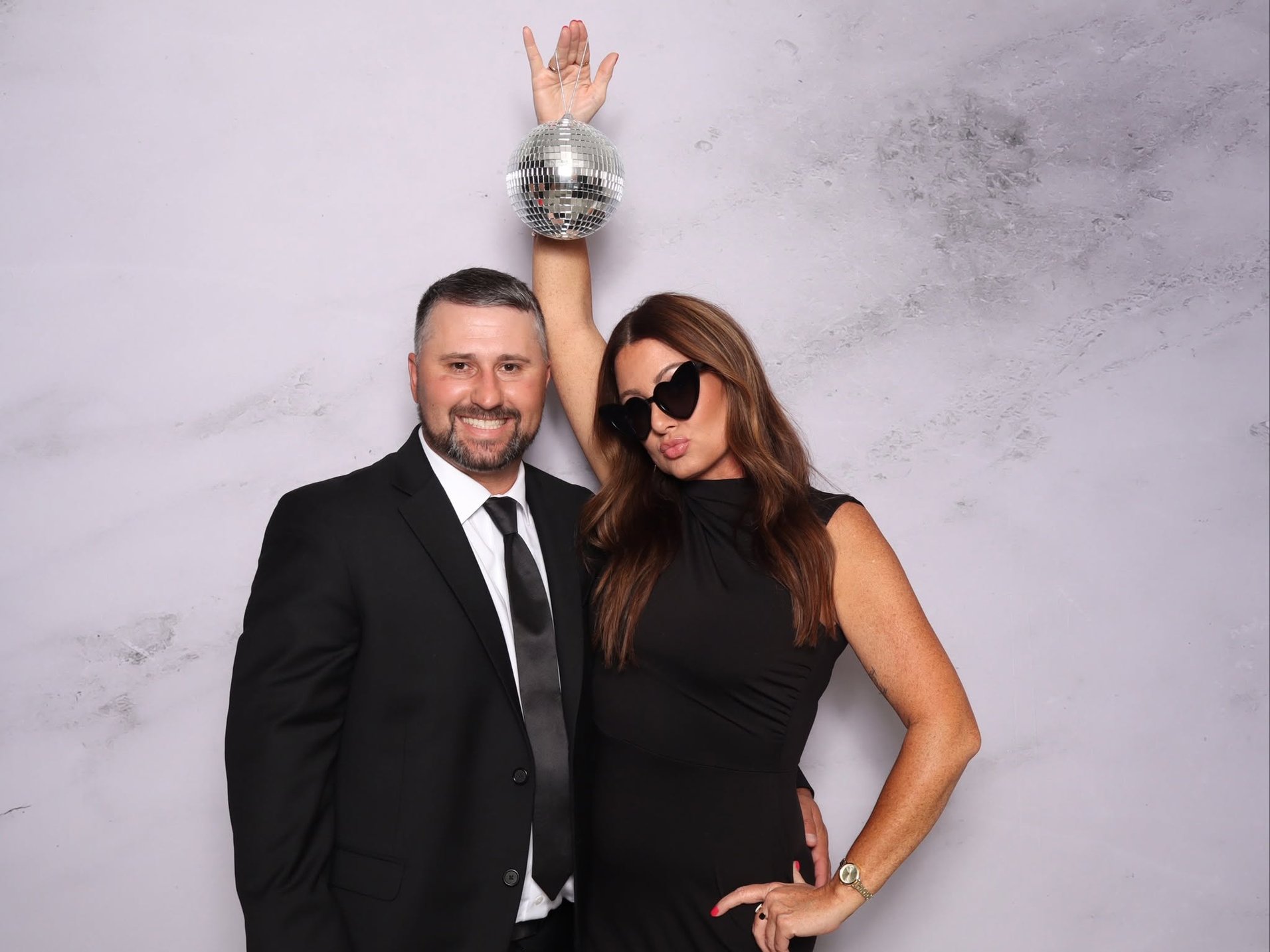 Two guests dressed in black, one holding up a disco ball, at the photo booth.